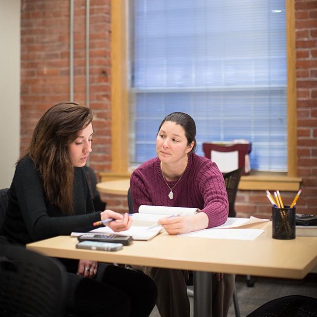 Student meeting with a professor and going over notes on a desk
