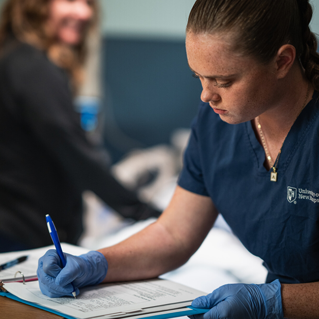 female nursing student writing in a log book