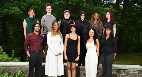 Group of students professionally dressed standing in two rows with trees in background.