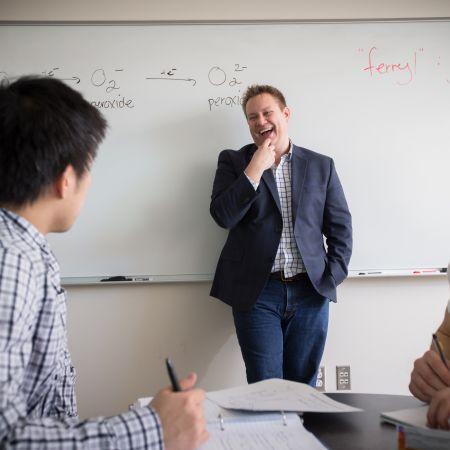 professor in front of whiteboard laughing