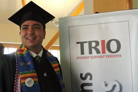 Grad student standing next to TRIO sign