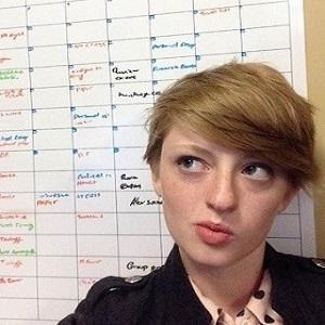 student posing in front of whiteboard schedule