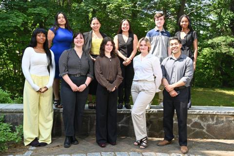 Group of students, professionally dressed, standing outside by a rock wall