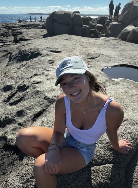 a white woman with a baseball hat on at the beach