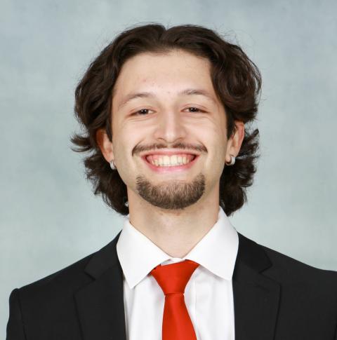a young man in a suit with brown hair and a goatee