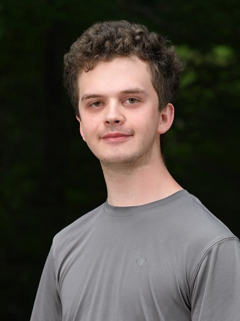 Male student head shot with trees in background.