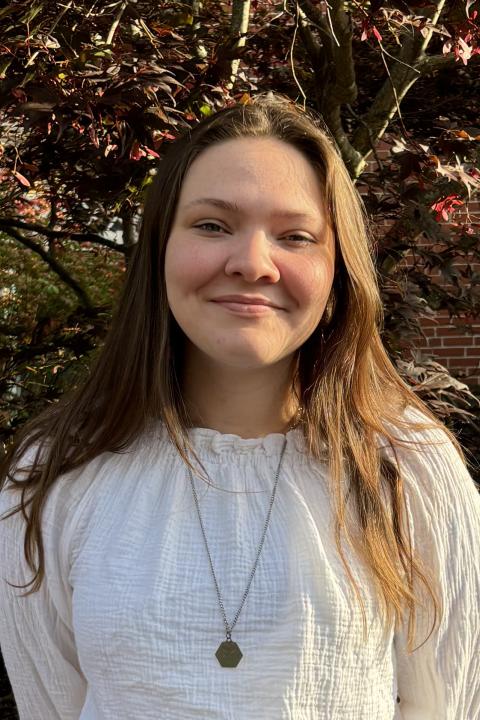 Feminine person with brown hair smiling. 