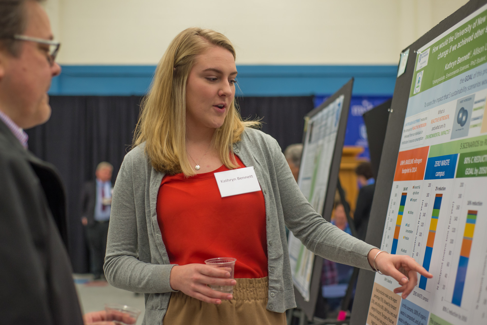 student presenting research pointing to poster