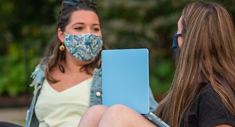 students socializing on the lawn with masks