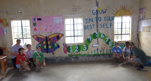 students kneeling in front of a wall with colorful murals
