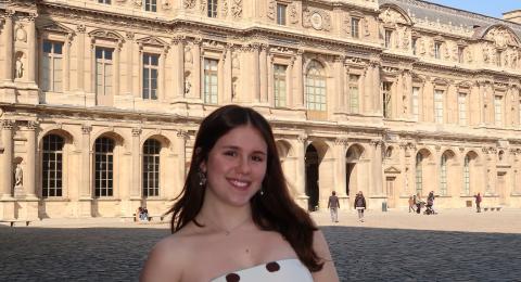person standing outside smiling with a large building in the background