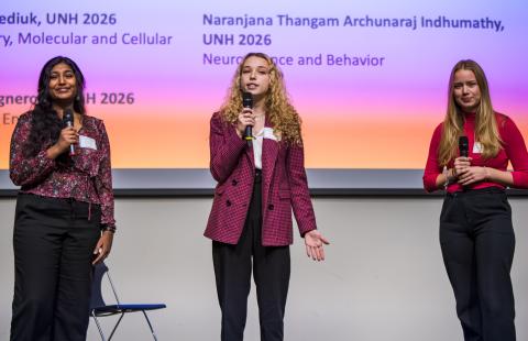 three students presenting on stage