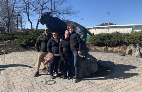 four people standing in front of a wildcat statue
