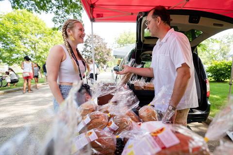 student talking to a vendor at a farmers market