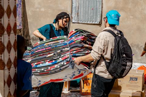 two students carrying mats