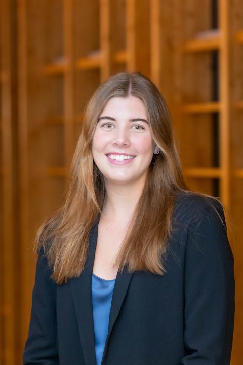 Professional headshot of Ella Longacre smiling with a suit jacket and blue blouse
