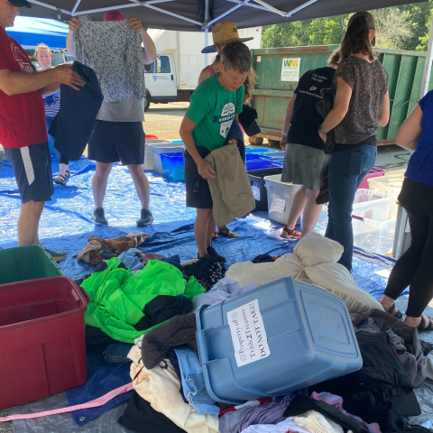 people outside sorting piles of clothing