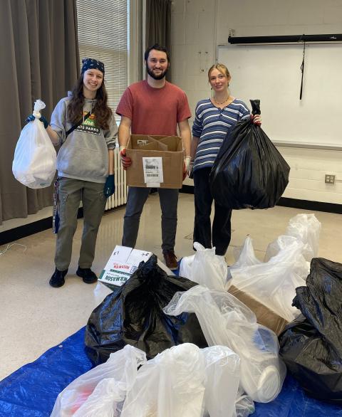 three people holding bags of trash