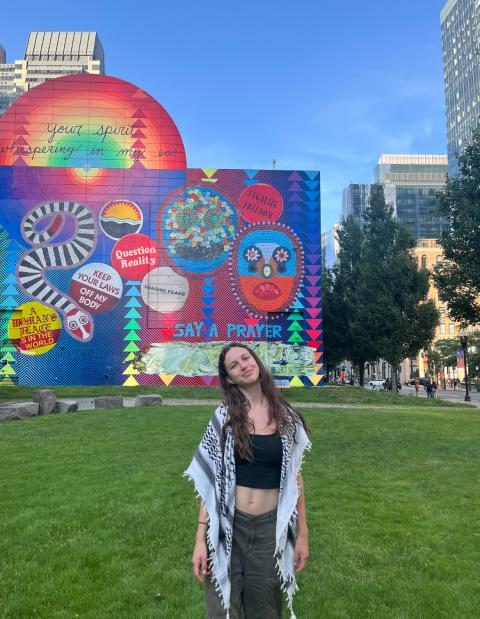 person standing outside on a lawn with a colorful mural in the background