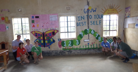 students kneeling in front of a wall with colorful murals