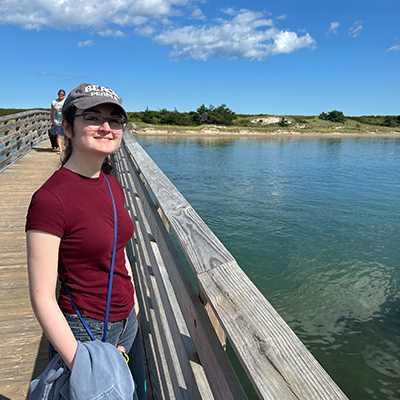 person standing outside next to the water smiling