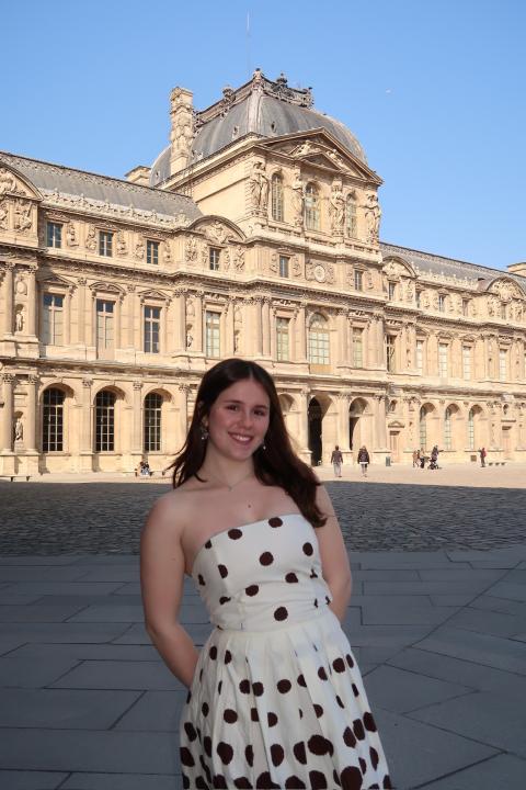 person standing outside smiling with a large building in the background