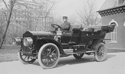 antique picture of a man driving an old car