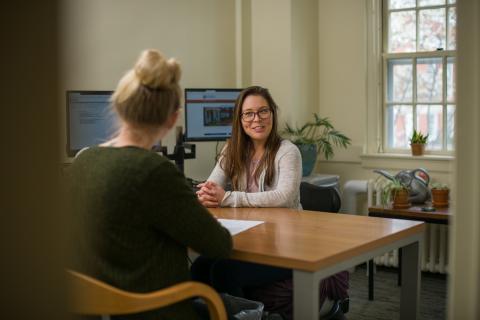 Student sitting at desk speaking with an academic advisor 