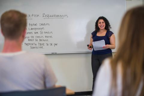 Professor at white board with students looking on in the foreground