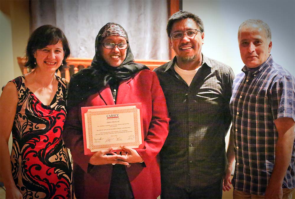A photo of Deqa Dhalac (second from left) standing next to instructors of the Master in Community Development program