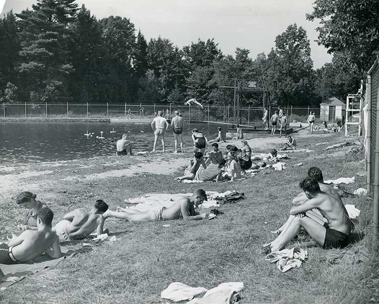 people sitting in the grass by the old UNH outdoor pool in 1961