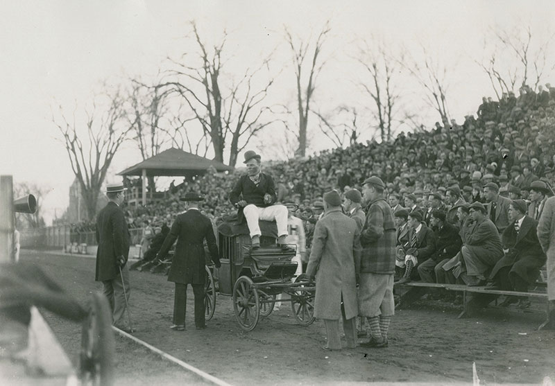 1928 Mayoralty campaign candidate riding in a car with managers standing around in front of crowds in the stands