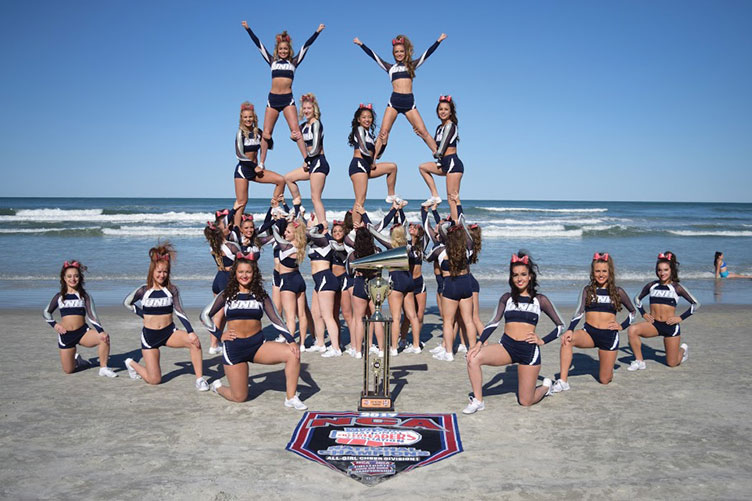 UNH cheerleaders posing in front of the ocean