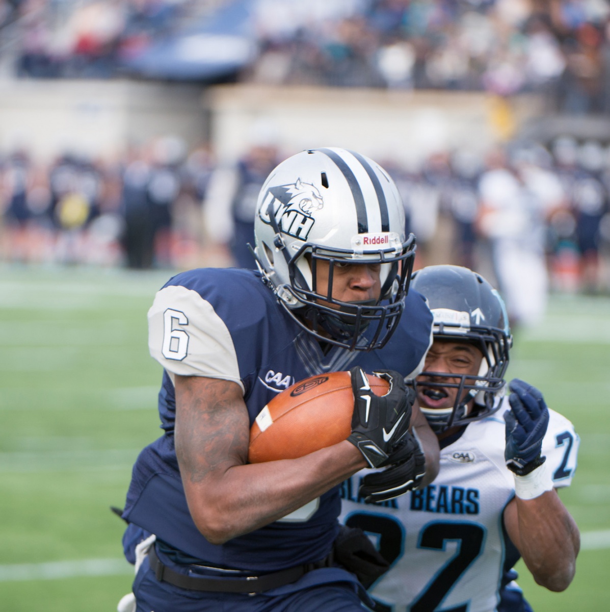 A UNH football player carrying the ball up the field