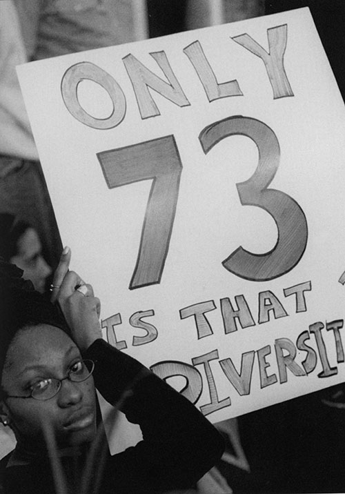 a UNH student holding a poster calling for increased recruitment of minority students and faculty