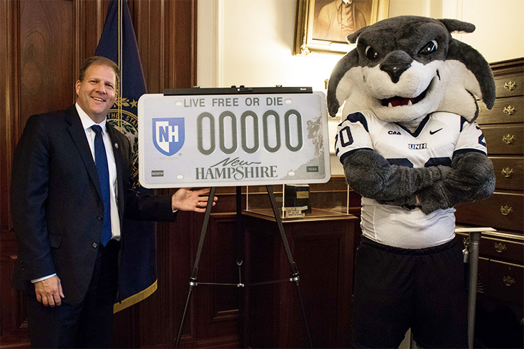 New Hampshire Gov. Chris Sununu poses with mascot Gnarlz at the unveiling of new UNH license plate decals Monday