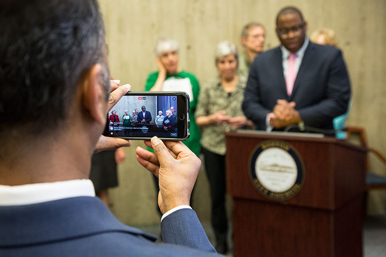 Boston city councilor and a man taking a cell phone photo of UNH alumnus Tito Jackson '99