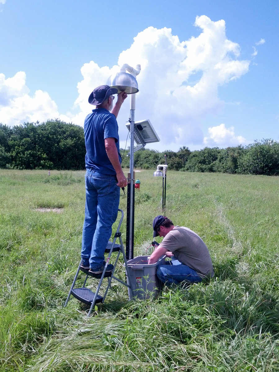 Two men in field install equipment