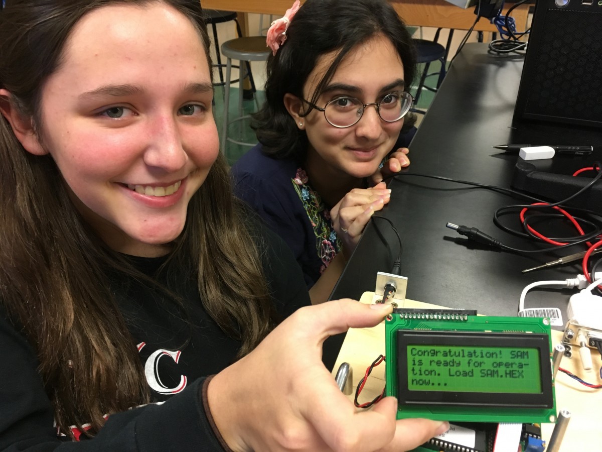 Two students hold small motherboard for magnetometer.