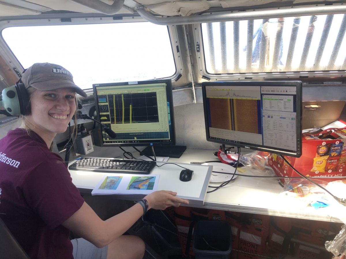 Natalie Cook examines seafloor mapping data aboard a ship.