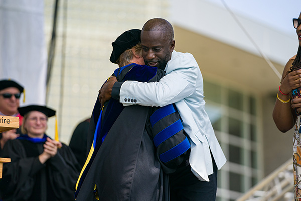 AJ's father hugging Dean Dillon on commencement stage