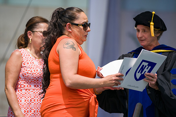 mom and aunt receiving certificate from Dean Dillon on commencement stage