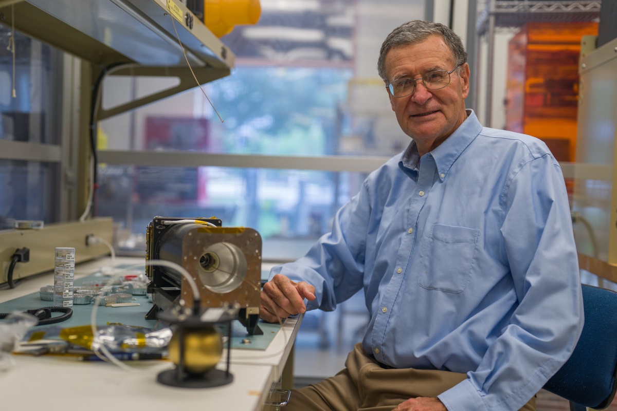 Roy Torbert sits in a lab next to space instruments.