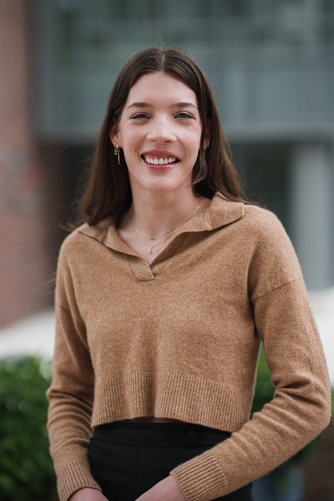 Portrait of woman in brown sweater standing outside 