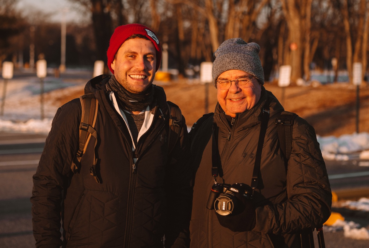 Adam Brockett poses with his father and both men have cameras around their necks