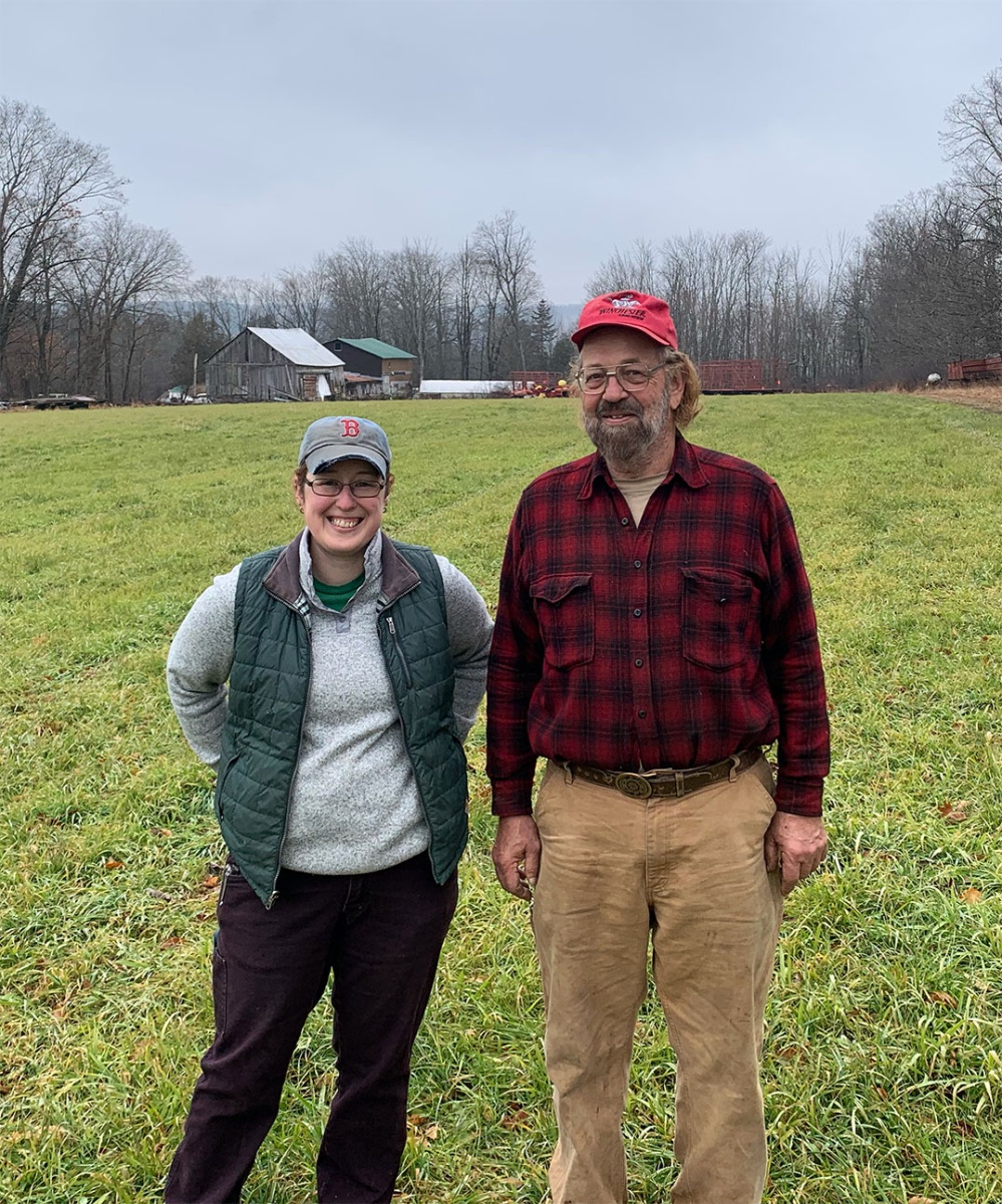 A photo of a white woman and an older white man standing in a farm field.