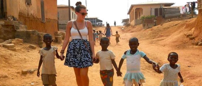a UNH study abroad student holding hands with children