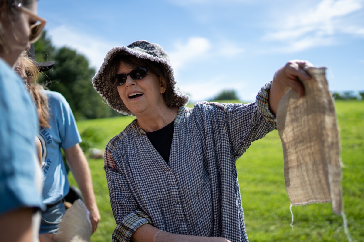 Woman in sunglasses and hat holds up a piece of linen