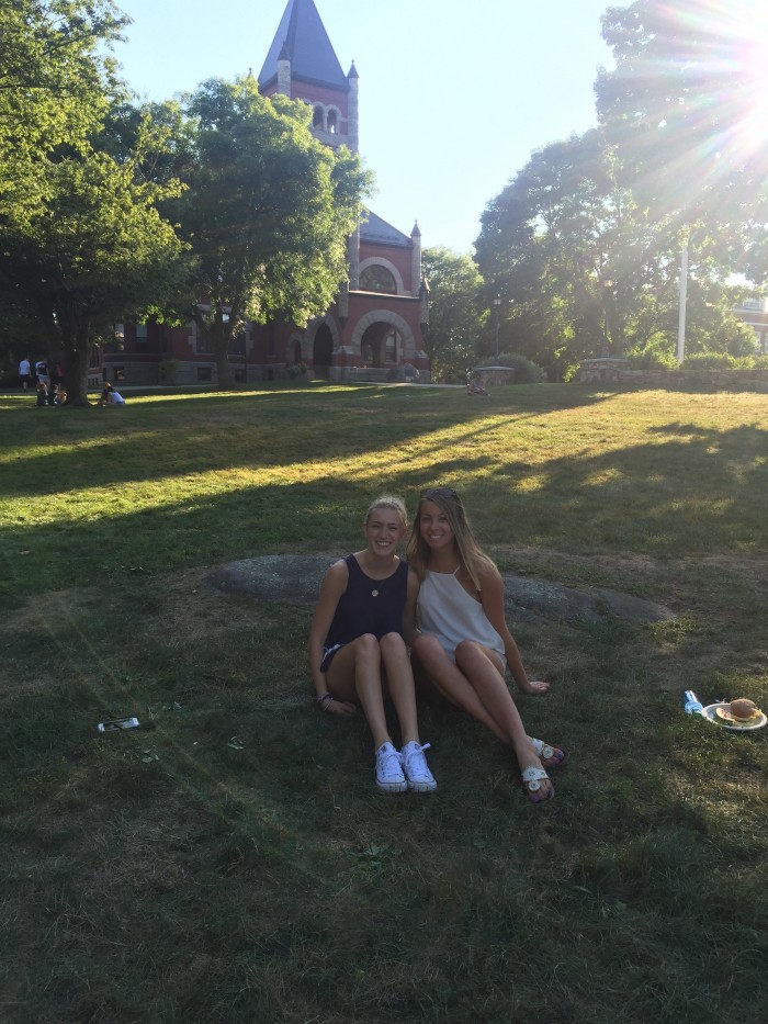 UNH student Charlotte Harris and a friend sitting in front of Thompson Hall