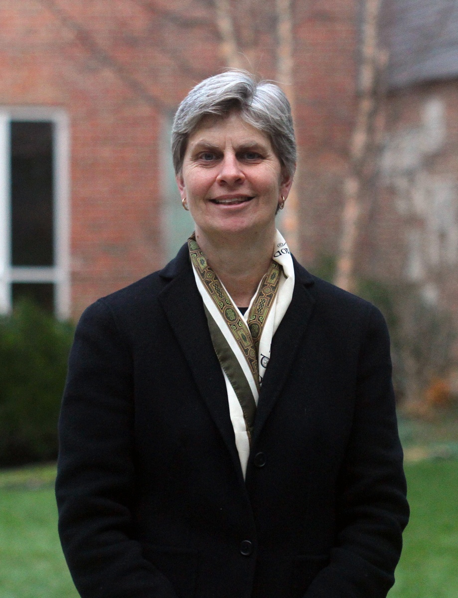 Professor Jennifer Jacobs looks at camera, wearing suit jacket and scarf